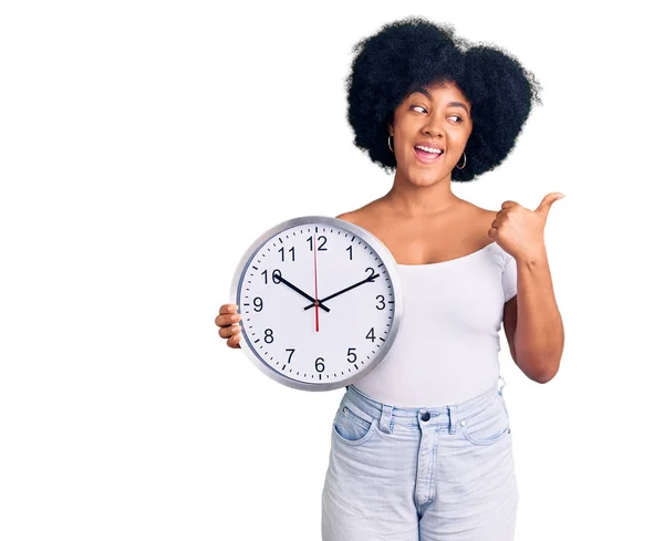 Jovem Afro Americana Segurando Grande Relógio Apontando Polegar Até Lado — Fotografia de Stock