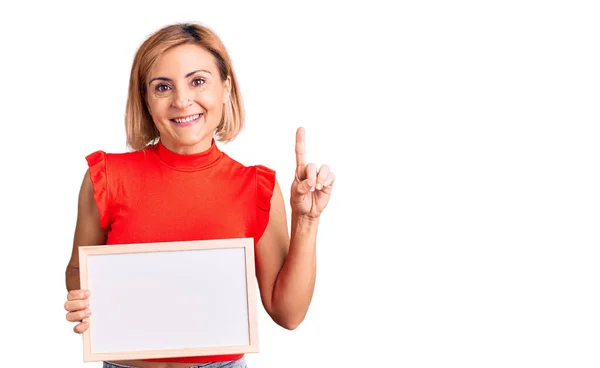 Young Blonde Woman Holding Empty White Chalkboard Surprised Idea Question — Stockfoto