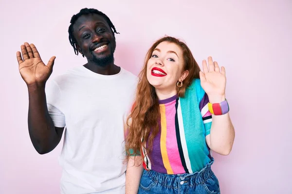 Interracial Couple Wearing Casual Clothes Waiving Saying Hello Happy Smiling — Stock Photo, Image