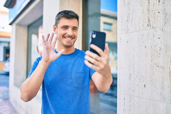若い白人男性が笑顔でビデオ通話をしますスマートフォンを使用して市内で — ストック写真