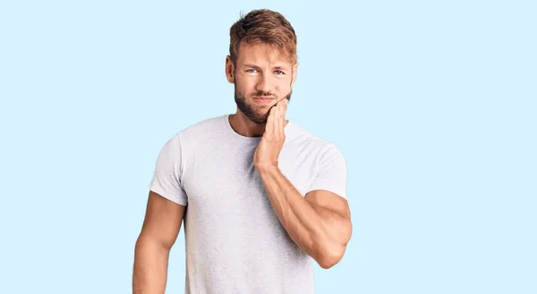 歯痛や歯の病気のために痛みを伴う表情で手で手に触れるカジュアルな白いTシャツを着た若い白人男性 歯科医 — ストック写真