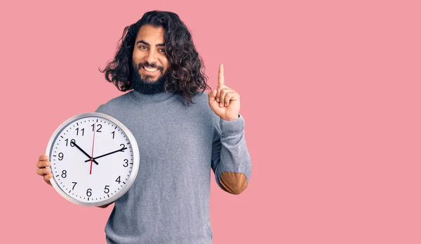 Hombre Árabe Joven Sosteniendo Gran Reloj Sorprendido Con Una Idea —  Fotos de Stock