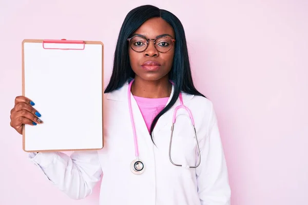 Young African American Woman Wearing Doctor Stethoscope Holding Clipboard Thinking — Stock Photo, Image