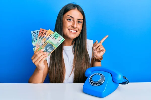 Piękna Latynoska Kobieta Zabytkowym Telefonem Trzymająca Australijskie Dolary Uśmiechająca Się — Zdjęcie stockowe