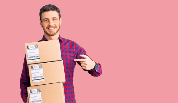 Bonito Jovem Com Urso Segurando Pacotes Entrega Sorrindo Feliz Apontando — Fotografia de Stock