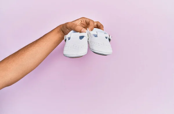 Main Hispanique Tenant Des Chaussures Bébé Sur Fond Rose Isolé — Photo