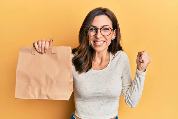 Young Brunette Woman Holding Take Away Paper Bag Screaming Proud — Stockfoto