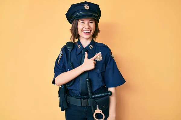 Young beautiful woman wearing police uniform cheerful with a smile of face pointing with hand and finger up to the side with happy and natural expression on face