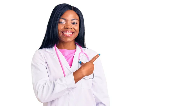 若いですアフリカ系アメリカ人女性を身に着けています医者聴診器陽気に笑顔で顔を指して手と指で幸せと自然な表情で側面まで — ストック写真