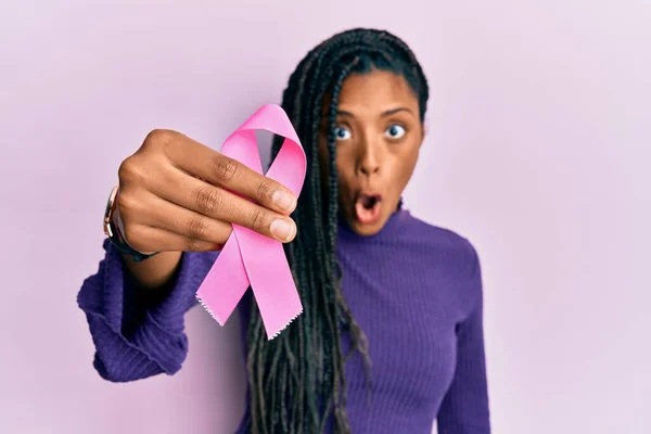 ピンクの癌リボンを持っているアフリカ系アメリカ人女性は怖がって 驚きのために口を開けて驚いて 不信の顔 — ストック写真