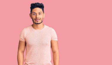 Yakışıklı Latin Amerikalı sıradan giyinen, pozitif ve mutlu görünen, kendine güvenen, gülümseyen, dişlerini gösteren genç adam. 