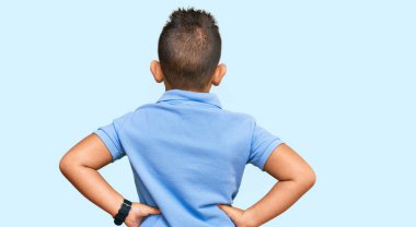 Sıradan kıyafetler giyen İspanyol çocuk kolları vücudunda geriye doğru bakıyor. 