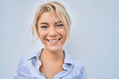 Genç sarışın kadın gülümseyerek şehirde mutlu mesut yürüyor..