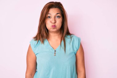 Orta yaşlı esmer, sıradan kıyafetler giyen, komik yüzlü, yanak şişiren İspanyol kadın. Havayla şişmiş ağız, çılgın bir ifade.. 