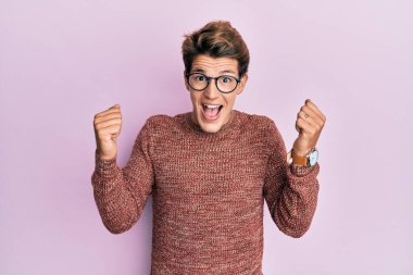 Sıradan süveter ve gözlük giyen yakışıklı beyaz adam kollarını kaldırıp, gözlerini açarak başarıyı kutluyor ve şaşırıyor. Kazanan konsept. 