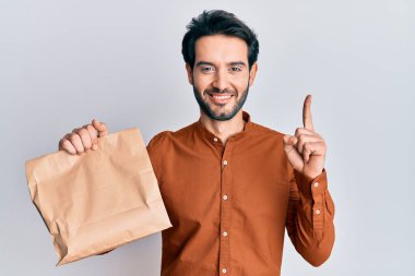 Elinde yiyecek tutan genç İspanyol bir adam bir fikirle ya da soru sorarak gülerek gülen bir numarayı işaret ediyor. 