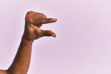 Siyah orta yaşlı bir kadının kolu ve eli pembe izole edilmiş arka plan üzerinde. Görünmez bir şeyi alıp götürüyor. Parmaklarıyla uzayı gösteren bir nesneyi tutuyor. 