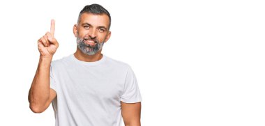Orta yaşlı, beyaz tişört giyen yakışıklı bir adam başarılı bir fikri işaret ediyor. Heyecanlı ve mutlu. Bir numara.. 