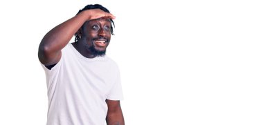 Örgülü beyaz tişörtlü, mutlu ve gülümseyen genç Afro-Amerikalı adam başlarını kaldırıp uzaklara bakıyor. arama kavramı. 