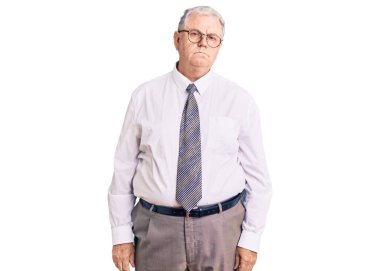 İş kıyafetleri giyen yaşlı gri saçlı adam yüzünde ciddi bir ifadeyle rahatladı. Basit ve doğal bir şekilde kameraya bakıyorsun.. 