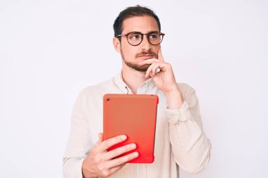 Genç yakışıklı bir adam dokunmatik ped kullanıyor ciddi bir yüz soru hakkında düşünüyor çene üzerinde elle, kafa karıştırıcı bir fikir hakkında düşünceli 