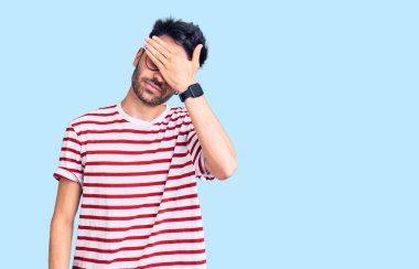 Latin asıllı genç bir adam, sıradan kıyafetler giyip gözlerini eliyle kapatıyor, ciddi ve üzgün görünüyor. Görme, saklama ve reddetme konsepti 