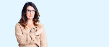 Güzel, genç, esmer, sıradan kıyafetler ve gözlük takan bir kadın endişeli ve endişeli bir ifade takınıyor. 