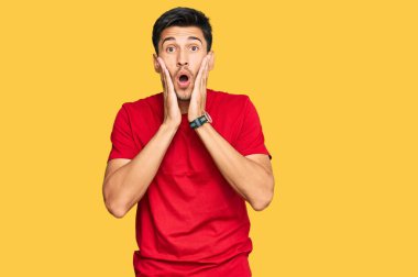 Kırmızı tişört giyen genç yakışıklı. Korkmuş ve şok olmuş. Şaşırmış ve şaşırmış. 