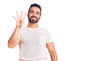İspanyol asıllı genç adam, gündelik giysiler giyip dört numarayı gösterip işaret ederken kendinden emin ve mutlu bir şekilde gülümsüyor.. 