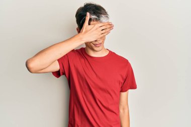 Latin asıllı genç bir adam, sıradan kıyafetler giyip gözlerini eliyle kapatıyor, ciddi ve üzgün görünüyor. Görme, saklama ve reddetme konsepti 