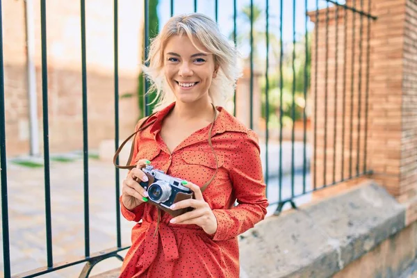 年轻的金发女人在城市里散步时 用老式相机开心地微笑着 — 图库照片