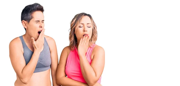 Couple Women Wearing Sportswear Bored Yawning Tired Covering Mouth Hand — Stock Photo, Image