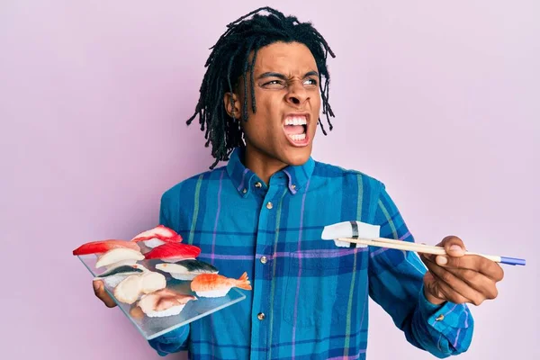Junger Afrikanisch Amerikanischer Mann Isst Sushi Mit Essstäbchen Wütend Und — Stockfoto