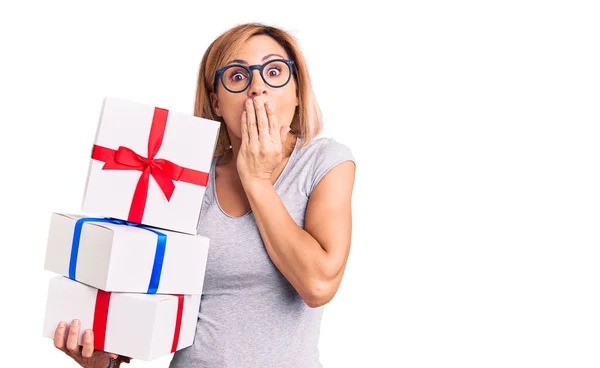 Young Blonde Woman Wearing Glasses Holding Gift Covering Mouth Hand — Stockfoto