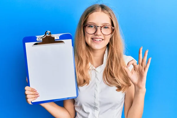 Beautiful Young Caucasian Girl Holding Clipboard Blank Space Doing Sign — Stockfoto