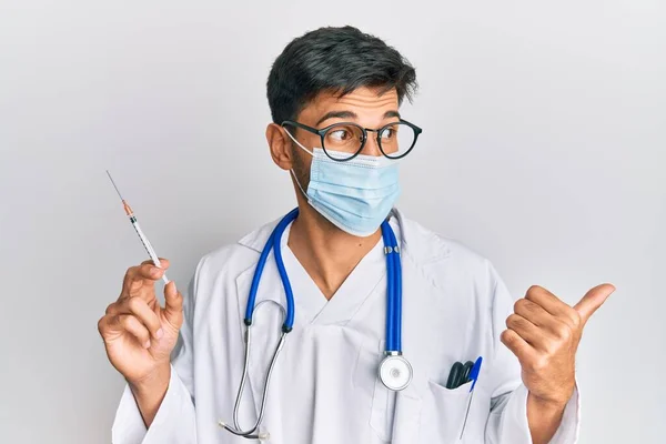 Młody Przystojny Mężczyzna Noszący Mundur Lekarza Maskę Medyczną Trzymający Strzykawkę — Zdjęcie stockowe