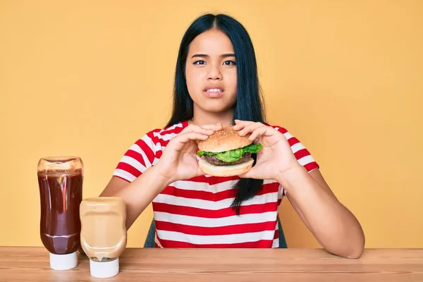 Fiatal Ázsiai Lány Eszik Egy Ízletes Klasszikus Burger Tudatlan Zavaros — Stock Fotó