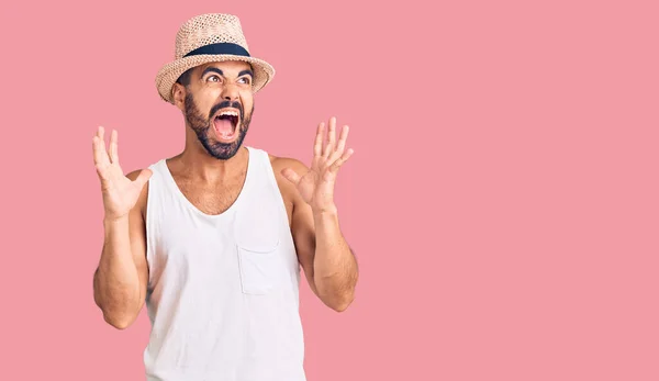 カジュアルな夏の帽子をかぶっている若いヒスパニック系の男は狂気と怒鳴り 積極的な表現と腕を上げて叫んでいた フラストレーションコンセプト — ストック写真