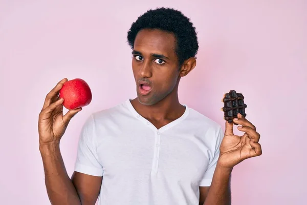 Hezký Africký Muž Drží Červené Jablko Čokoládové Vafle Šoku Tvář — Stock fotografie