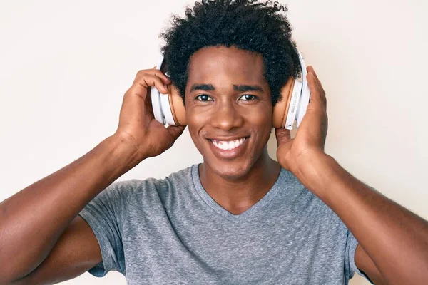 Красивый Африканский Американец Африканскими Волосами Слушает Музыку Используя Наушники Улыбаясь — стоковое фото