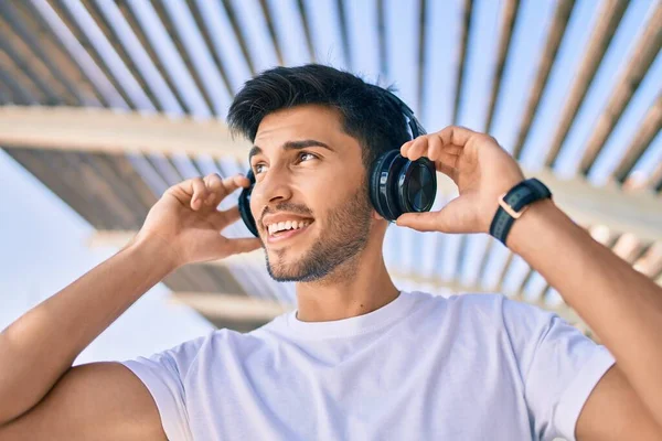 Jovem Latino Sorrindo Feliz Ouvindo Música Usando Fones Ouvido Cidade — Fotografia de Stock