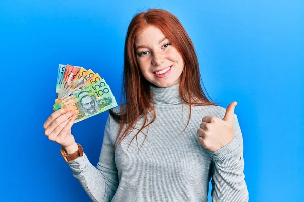 Młoda Ruda Dziewczyna Trzyma Australijskie Dolary Uśmiechnięte Szczęśliwy Pozytywny Kciuk — Zdjęcie stockowe