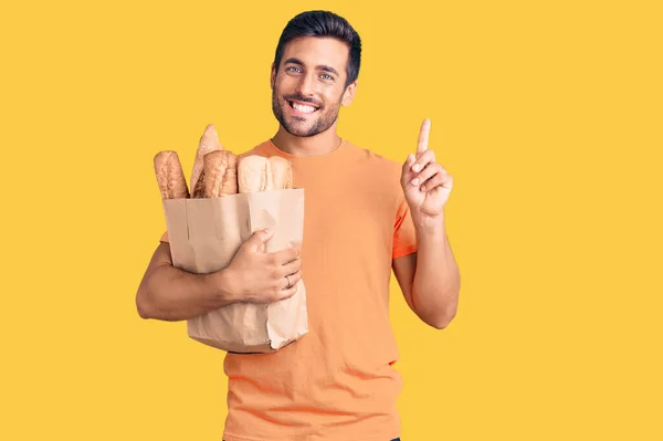 Young Hispanic Man Holding Paper Bag Bread Surprised Idea Question — Stock Photo, Image