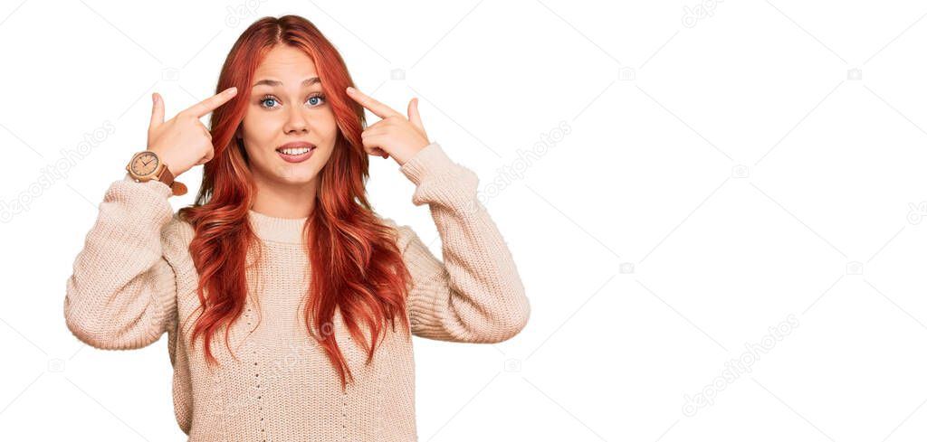 Young redhead woman wearing casual winter sweater smiling pointing to head with both hands finger, great idea or thought, good memory 