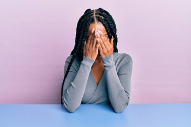 Güzel İspanyol kadın, gündelik giysiler giyip masaya oturmuş ağlarken suratını ellerle kapatıyor. depresyon kavramı. 