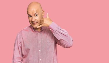 Orta yaşlı, kel, sıradan kıyafetler giyen, gülümseyen, el ve parmaklarıyla telefonla konuşan bir adam. iletişim kavramları. 