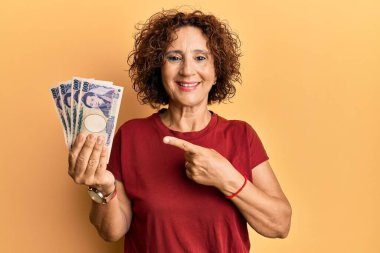 Güzel, orta yaşlı, olgun bir kadın elinde 5000 japon yeni banknotuyla elini ve parmağını göstererek mutlu mesut gülümsedi. 