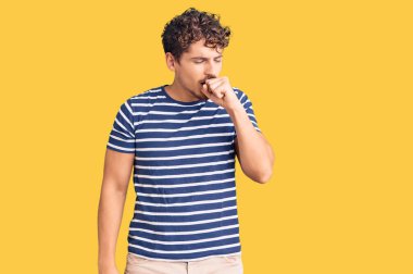 Kıvırcık saçlı, günlük kıyafetler giyen, kendini iyi hissetmeyen ve soğuk algınlığı veya bronşitin belirtisi olarak öksüren genç yakışıklı bir adam. sağlık hizmeti kavramı. 