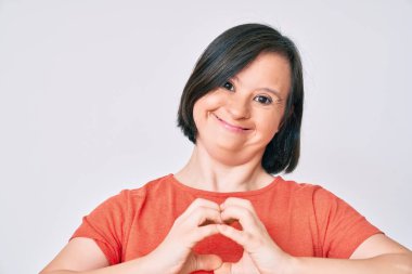 Down sendromlu esmer kadın, sıradan kıyafetler giyip, aşkla gülümsüyor. Elleriyle kalp sembolü ve şekli gösteriyor. romantik kavram. 