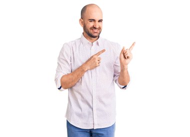 Zarif gömlekli genç adam gülümsüyor ve kameraya bakıyor iki eliyle ve parmaklarıyla kenarı işaret ediyor.. 